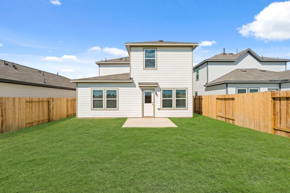 A backyard with a fence and a house.