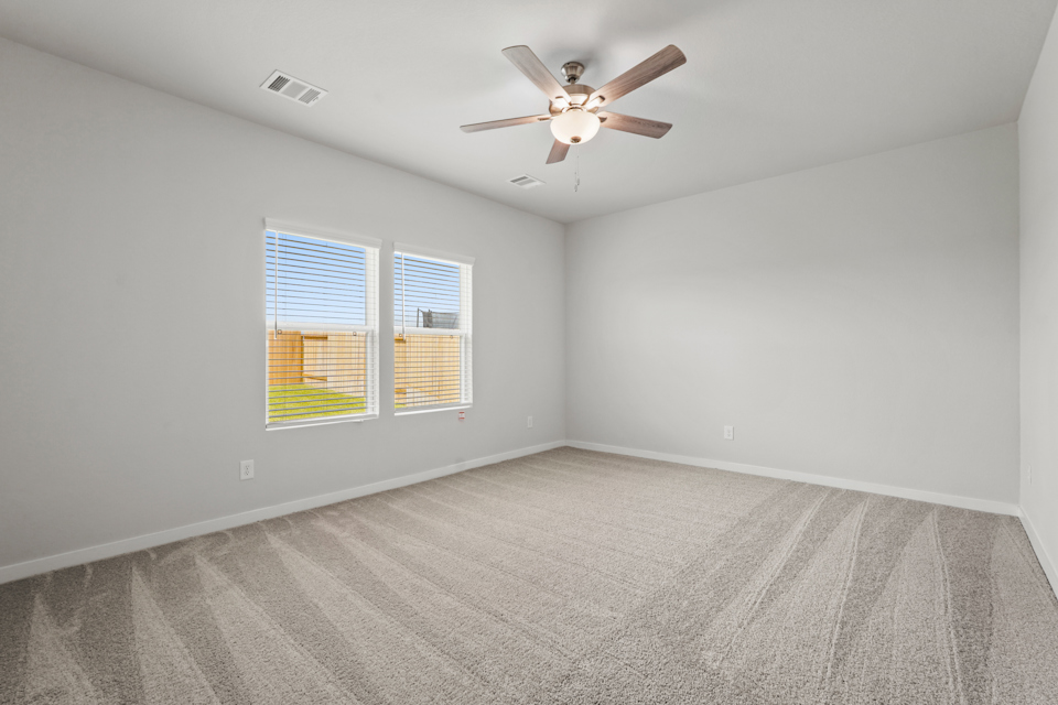 A room with a ceiling fan and a window with blinds.