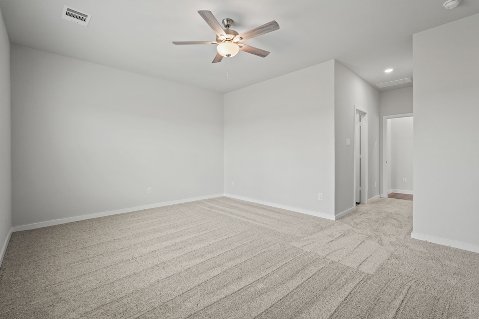 A room with a ceiling fan and a carpet.