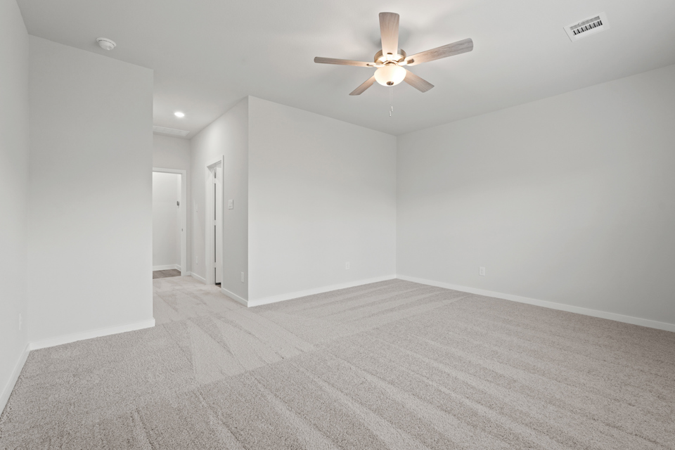 A room with a ceiling fan and a carpet.