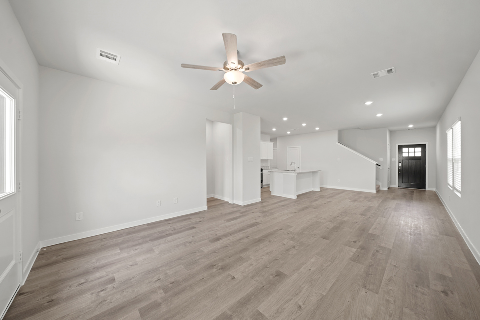 A large empty room with a ceiling fan and a wood floor.