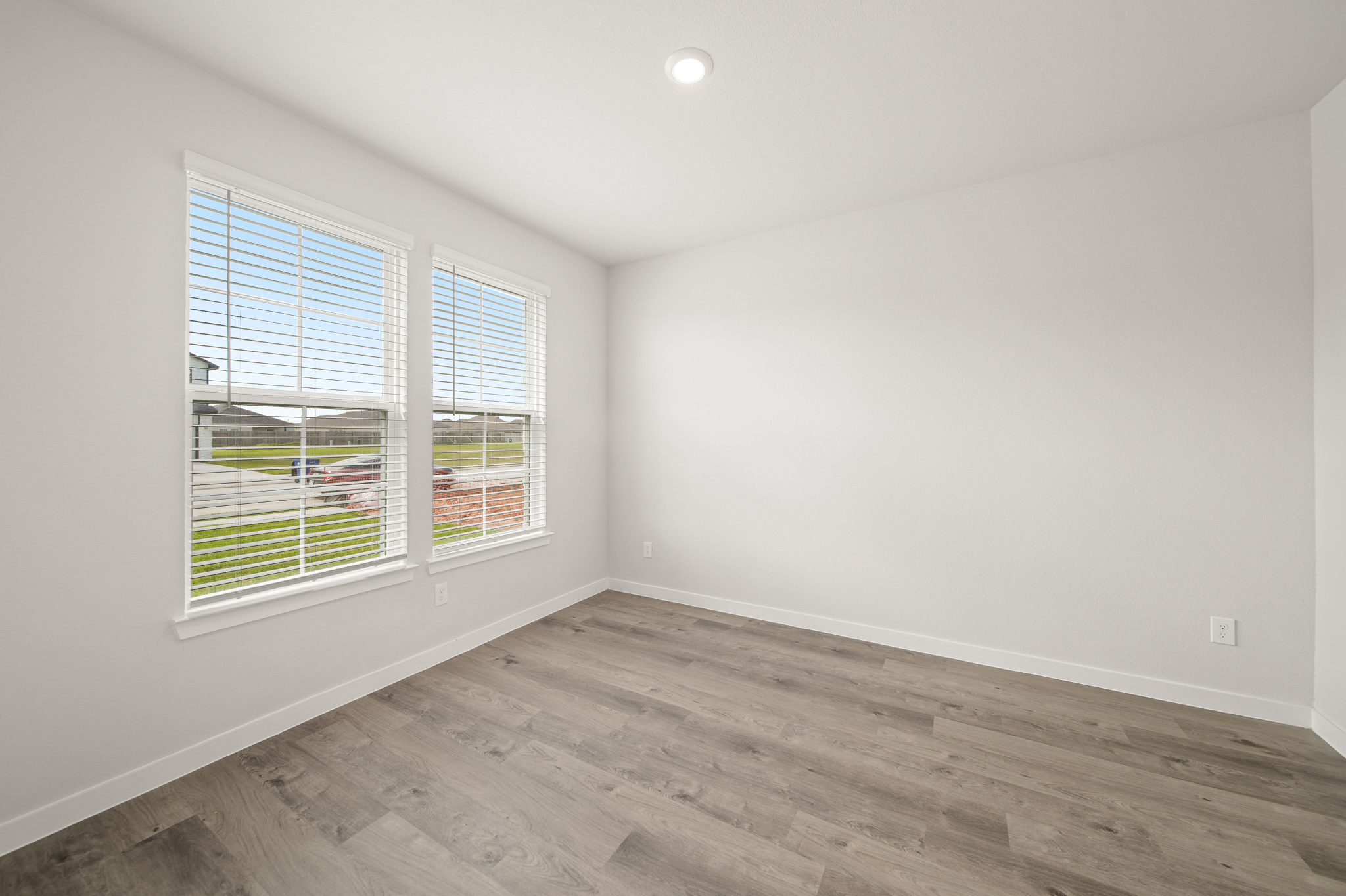 A room with a wood floor and a window with blinds.