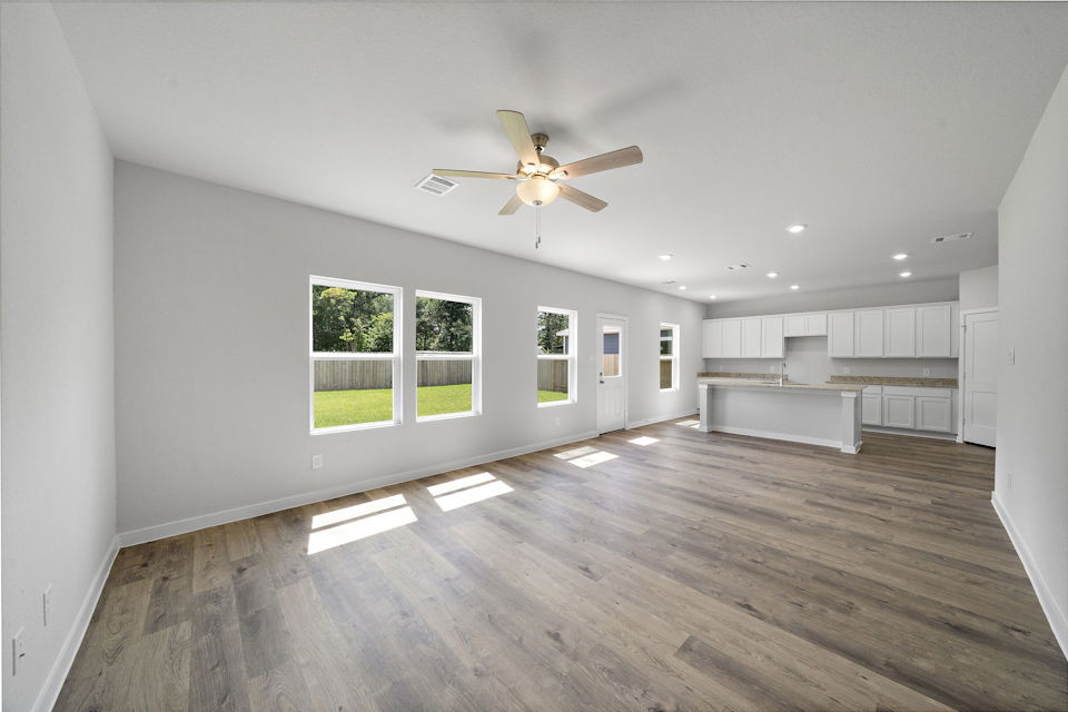 A large empty room with a ceiling fan and a wood floor.