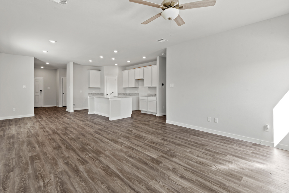 A large empty room with a wood floor and a white table.