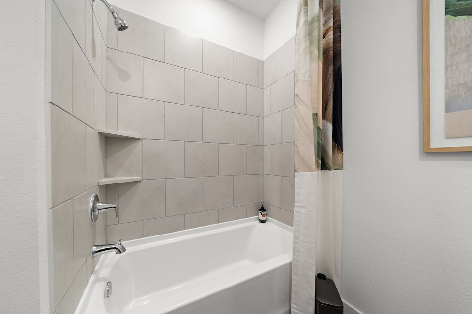 A bathroom with a bathtub and a tile wall.