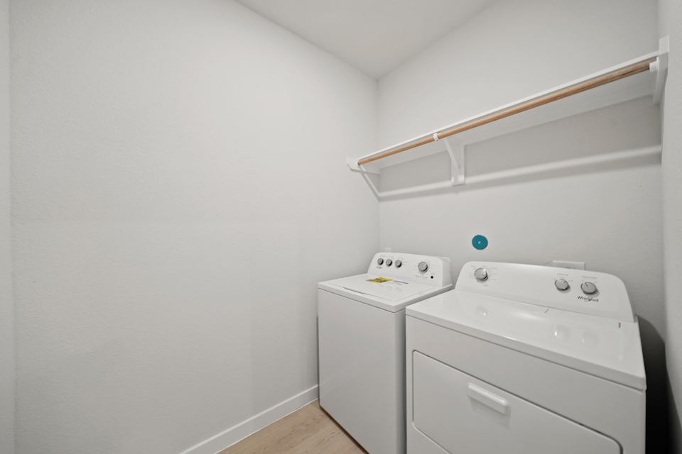 A white laundry room with a white shelf and a white wall.
