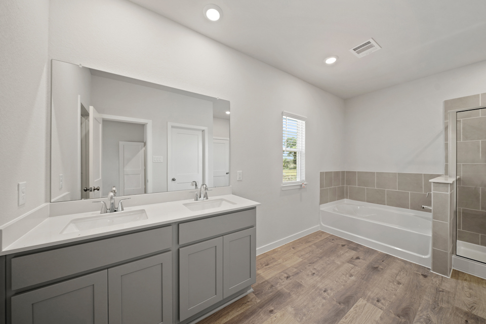 A bathroom with a tub sink and a mirror.