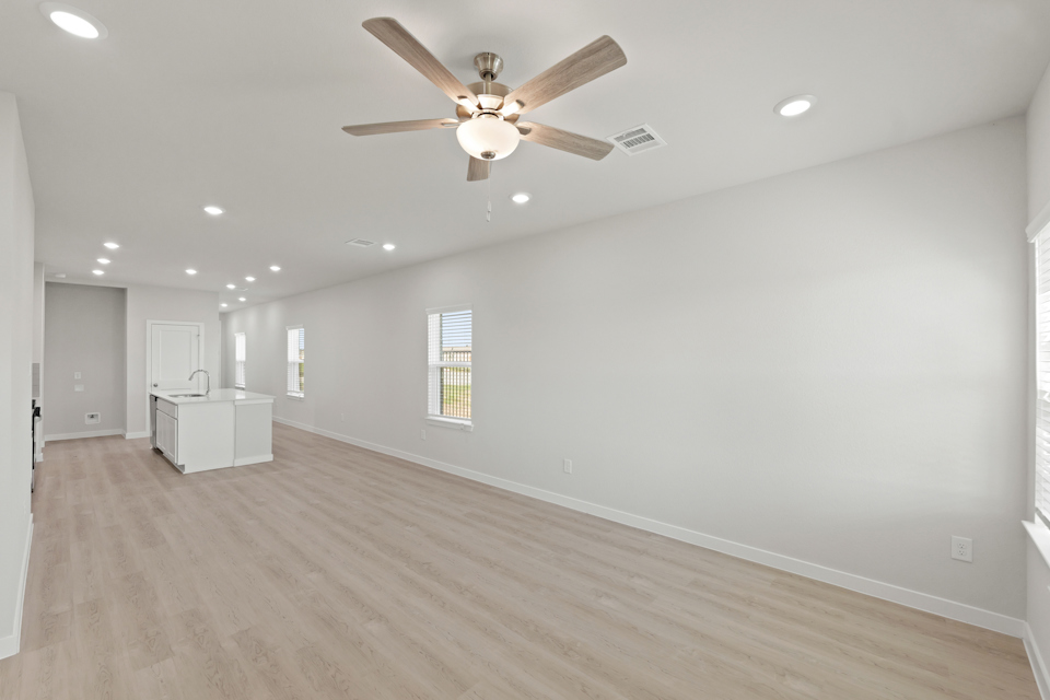 A room with a ceiling fan and wood floors.