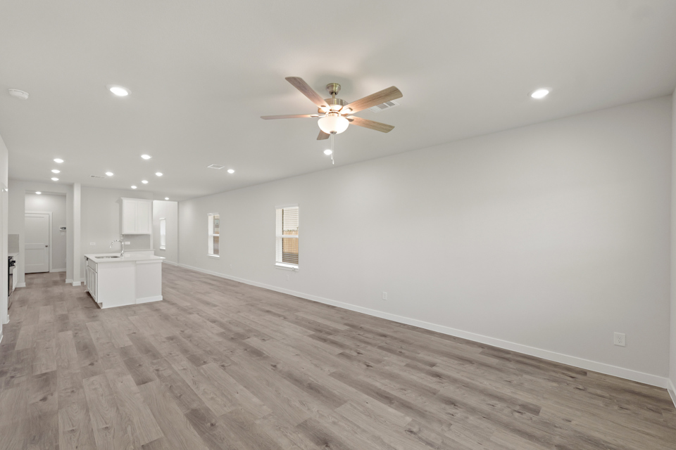 A room with a ceiling fan and a wood floor.
