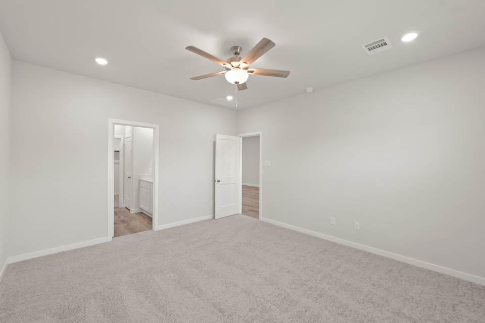 A room with a ceiling fan and a carpet.