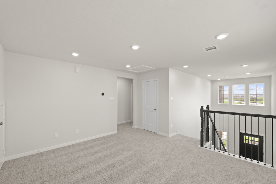 A room with a black railing and white walls.