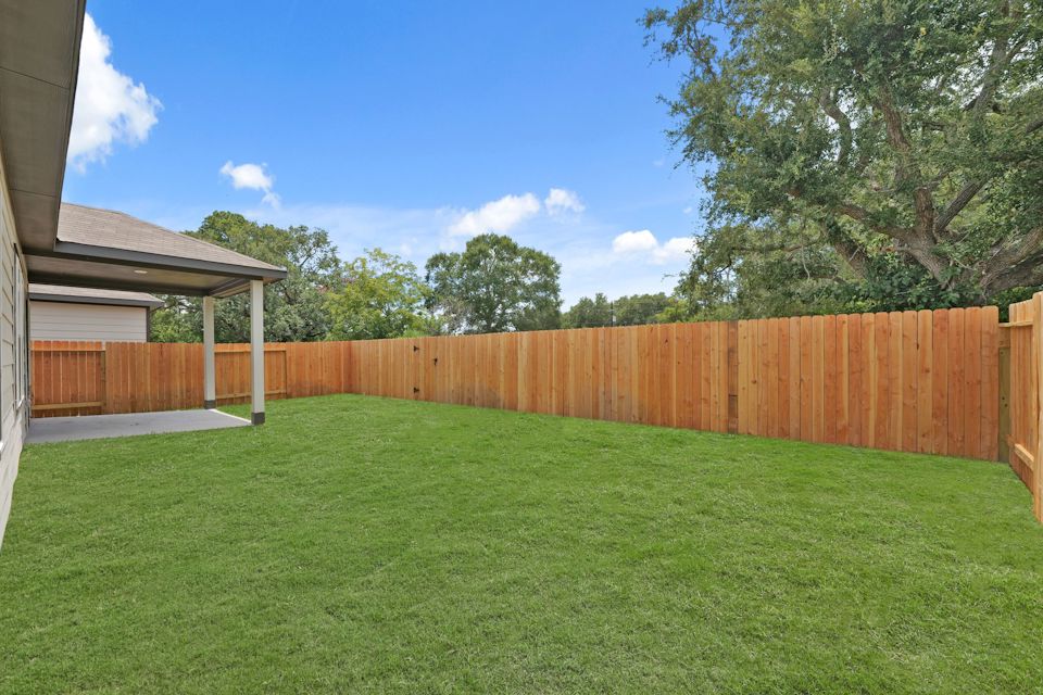 A fenced in yard with a wood fence and trees in the background.