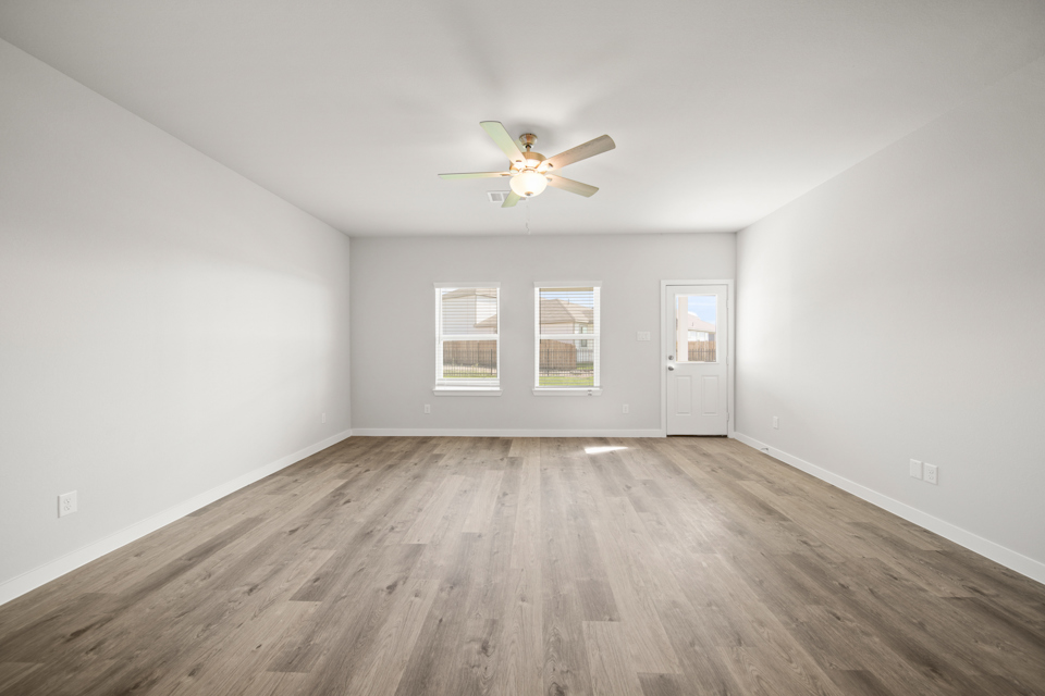A room with a ceiling fan and a wood floor.