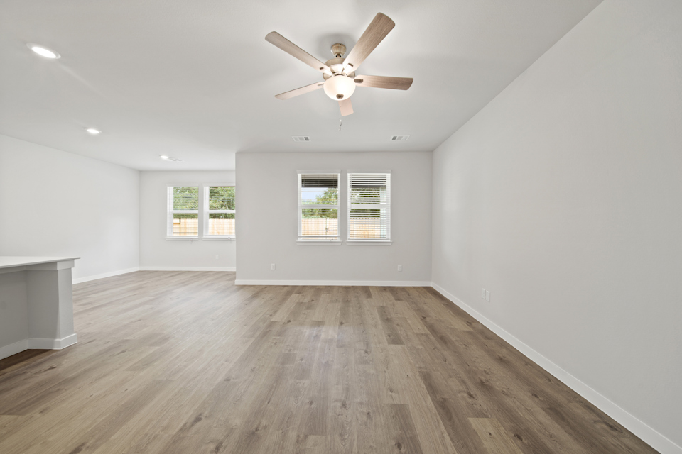A room with a ceiling fan and a wood floor.
