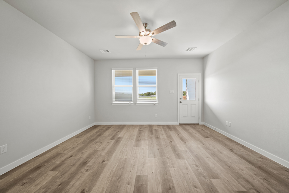 A room with a ceiling fan and a wood floor.