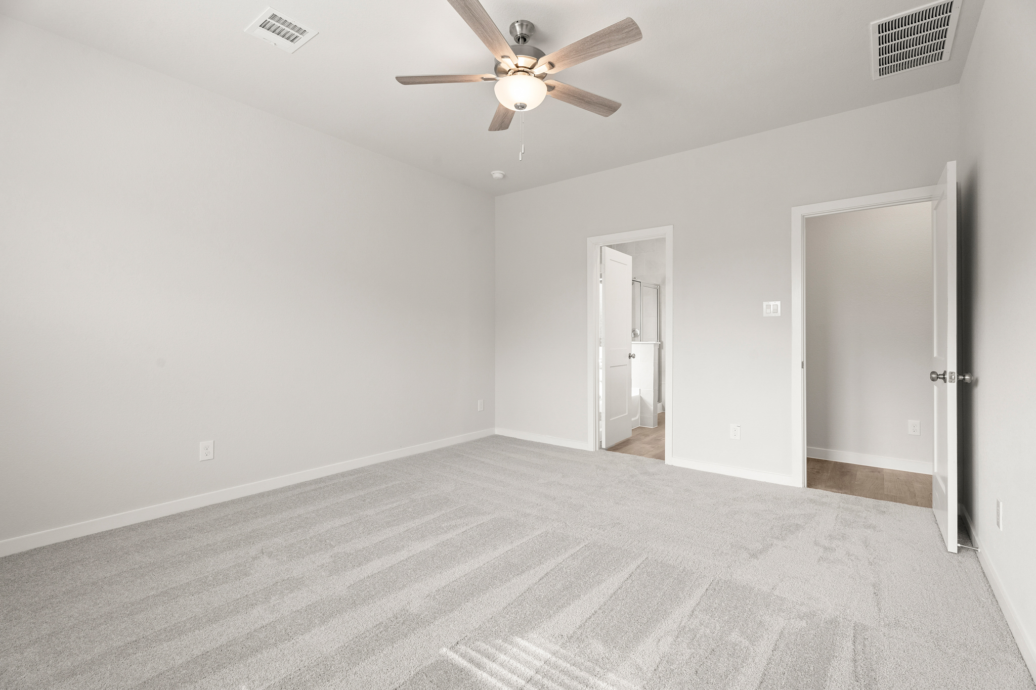 A room with a ceiling fan and a carpet.