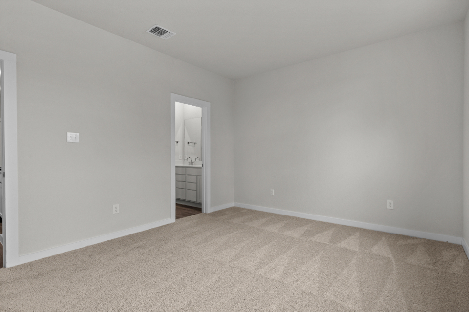 A room with a carpet and a white wall.