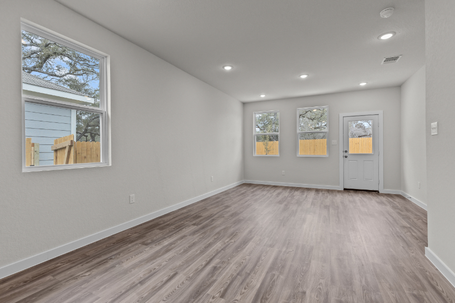 A room with a wood floor and a wood floor with a door and a window with a white.