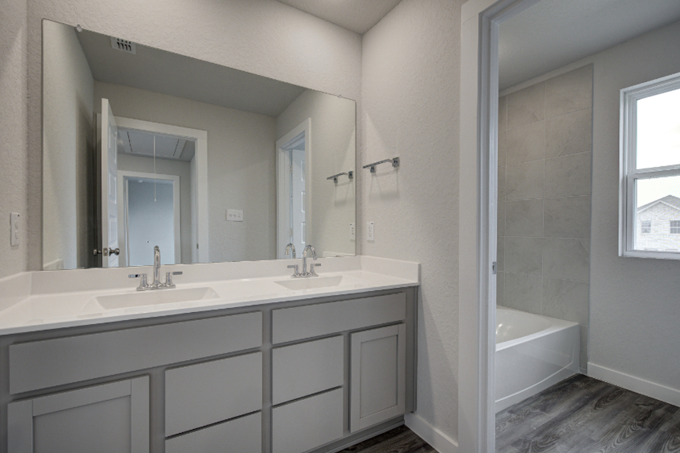 A bathroom with a tub sink and mirror.