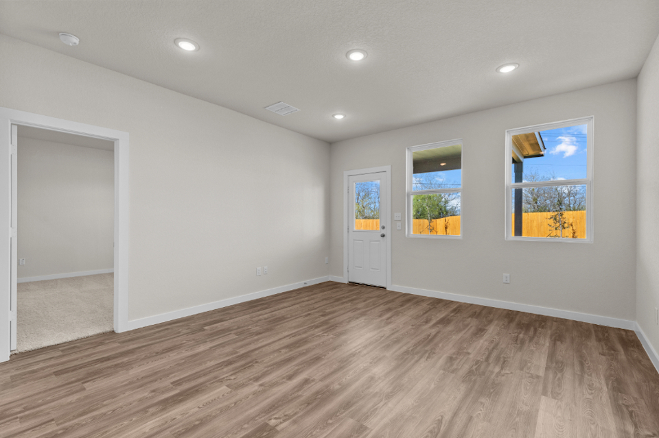 A room with a wood floor and a wood floor with a door and a window with a tree.