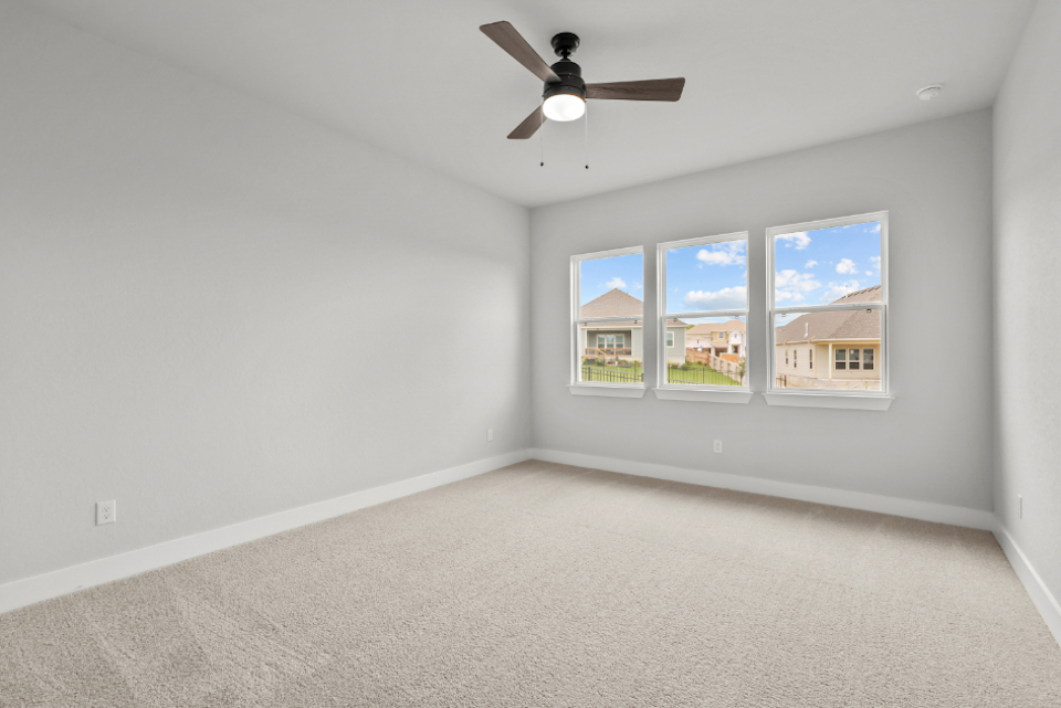 A room with a ceiling fan and a window with a view of the city.
