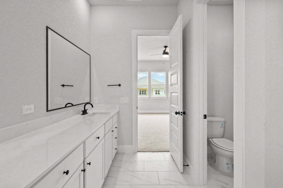 A bathroom with white cabinets.