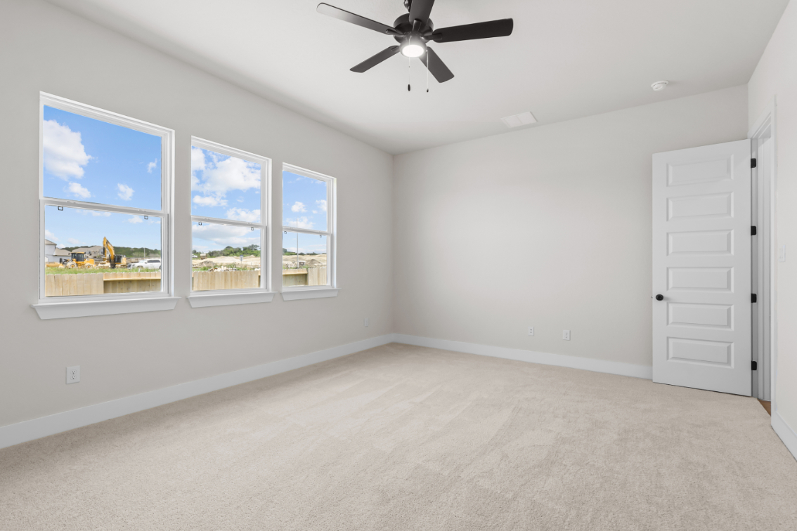 A room with a ceiling fan and a window with a view of the water.