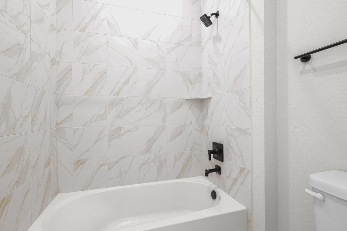 A white bathroom with a white tile wall.