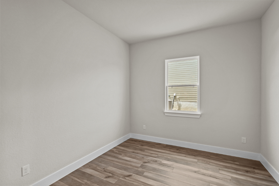 A room with a wood floor and a window with a couple of cats in it.