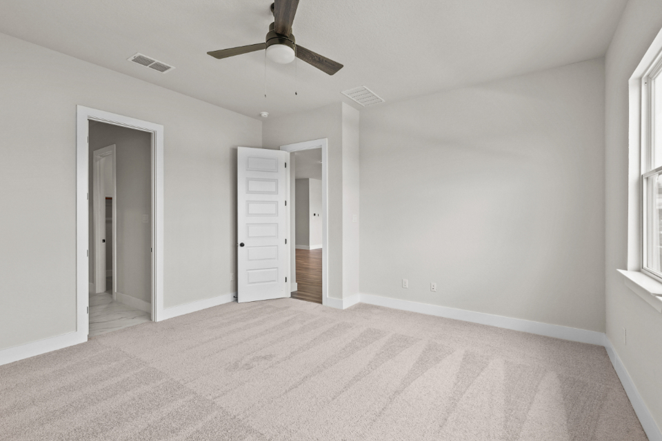 A room with a ceiling fan and white walls.
