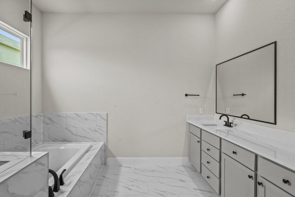 A bathroom with a tub sink and mirror.