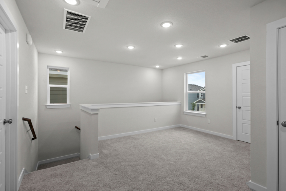 A large white room with a bathtub and a window.