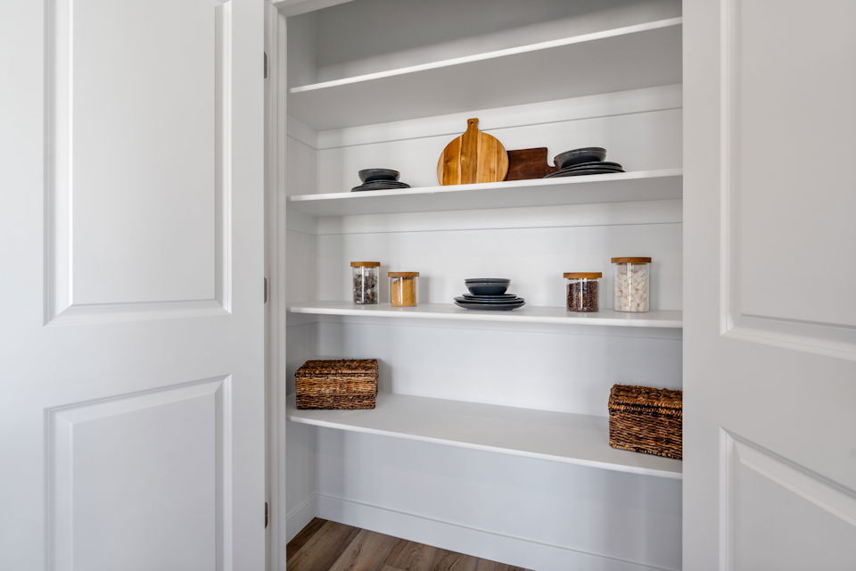 A white shelving unit with white cabinets and white walls.