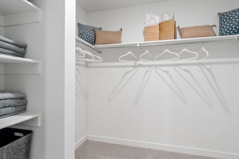 A white shelf with towels and pillows.