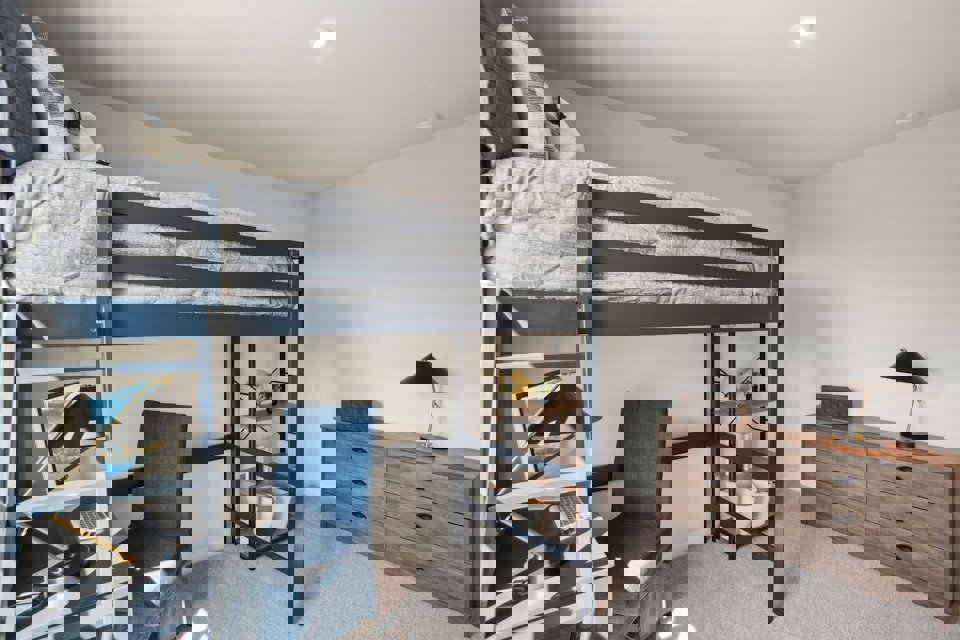 A bedroom with a bunk bed and a chair.