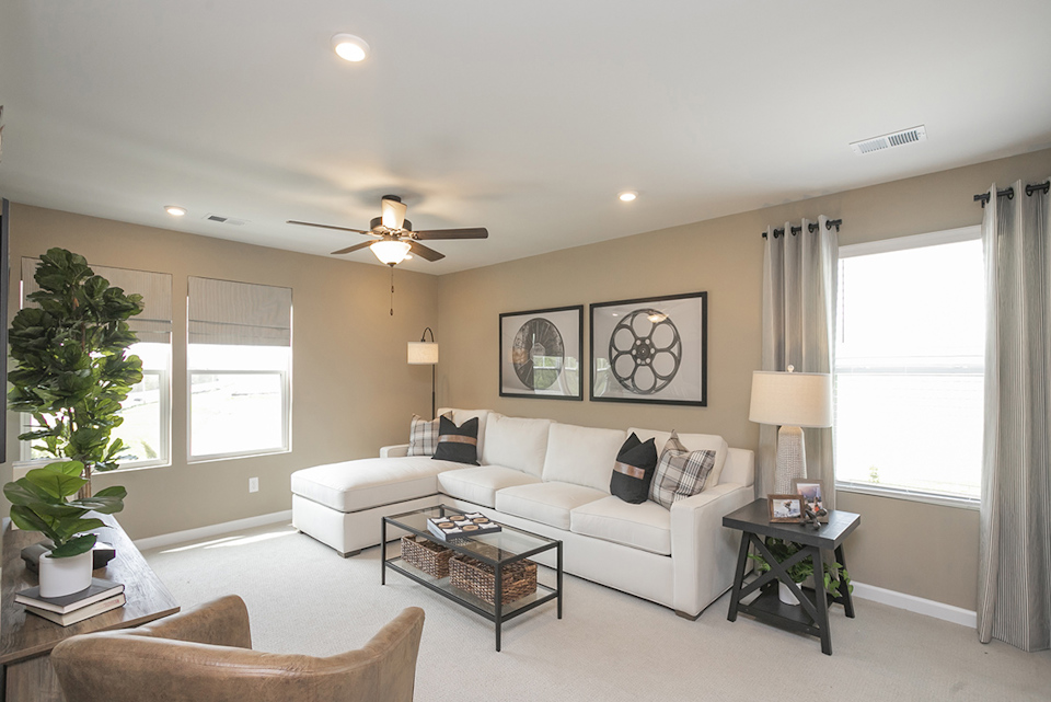 A living room with a white couch and a fan.