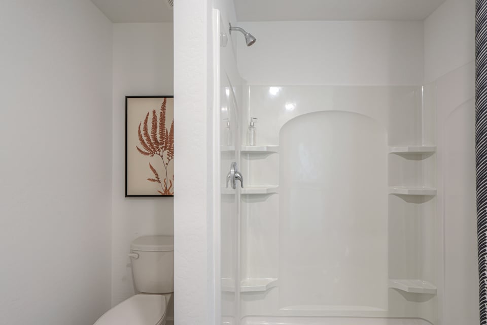 A bathroom with a shower unit and toilet.