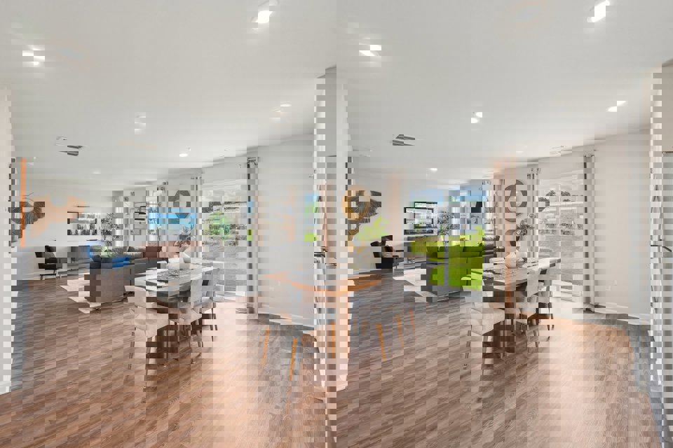 A large living room with a wood floor and a large dining table.